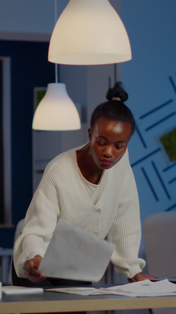 Vertical video Black bookkeeper working on financial reports checking statistics graphs