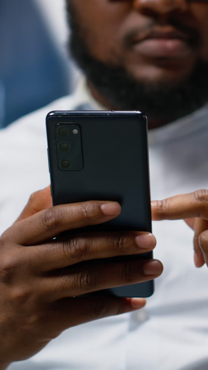 Vertical Video African american adult browsing his smartphone that walks along avenue