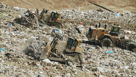 heavy machinery compacting trash at a large landfill