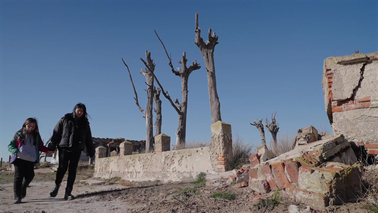 Madre e figlia che camminano tra rovine abbandonate a Epecuén, Argentina, sotto un cielo sereno