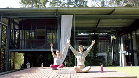 Focused-asian-female-friends-practicing-yoga-meditation-on-sunny-terrace,-slow-motion