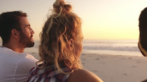 Young-adult-friends-relaxing-on-the-beach-at-sunset-4k