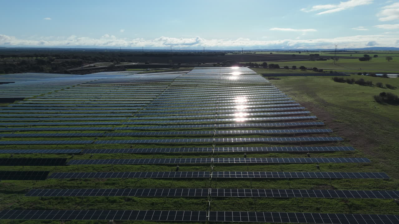 Drone shot of solar farm with sunlight reflections on panels, highlighting clean energy production, sustainability, and modern environmental technology