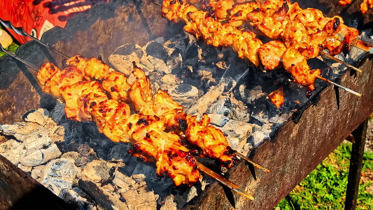 A few juicy meat sticks sizzle on a big outdoor BBQ grill under bright sunlight
