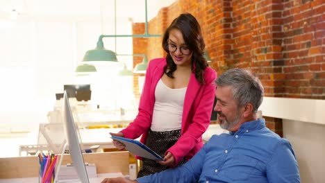 ejecutivos masculinos y femeninos discutiendo sobre la tableta digital en el escritorio