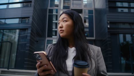 business chinese woman standing on the street in the city and texting phone