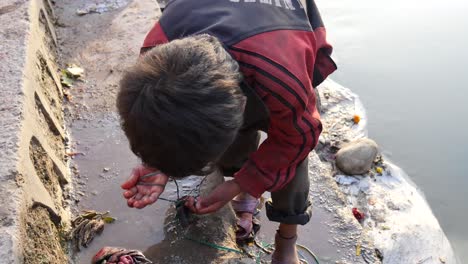 Niño-Nepalí-Recolectando-Dinero-Usando-Un-Imán-En-Un-Festival-De-Ayuno-En-Sankhu,-Nepal