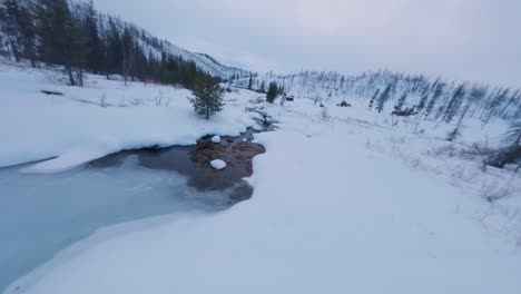 low flying over the icy stream in idaho city next to a yurt