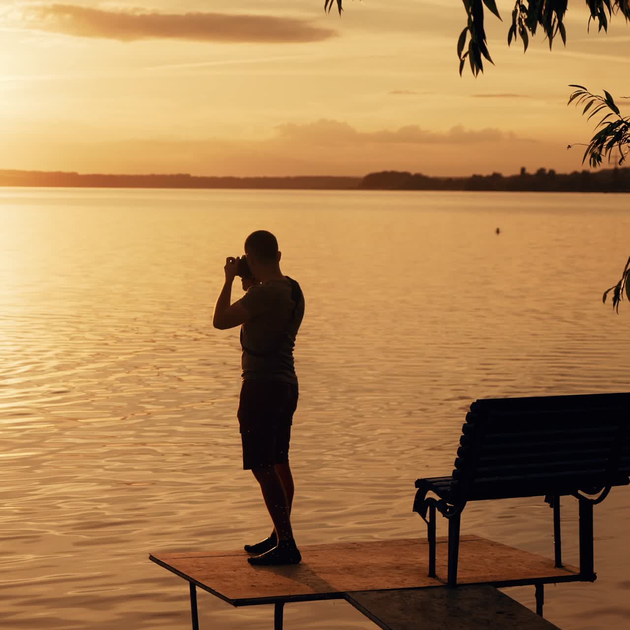 Photographer taking picture of sunset at local beach which is tourists point. Beautiful summer sunset.