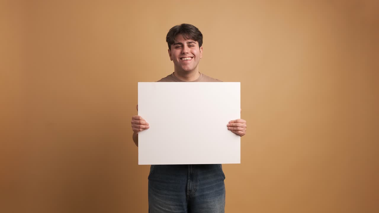 Cheerful man showing blank banner in studio