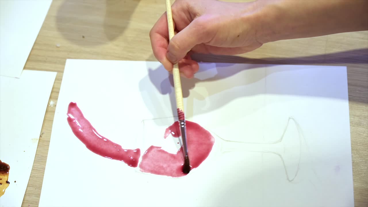 A woman in a studio painting on paper with red wine and brush, close view, slow motion
