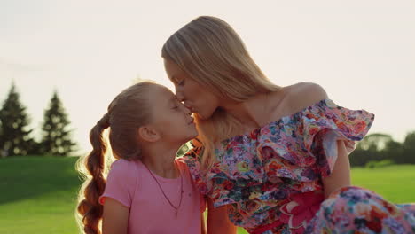 happy woman kissing adorable girl in city park