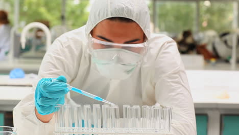 scientist pouring liquid in test tubes