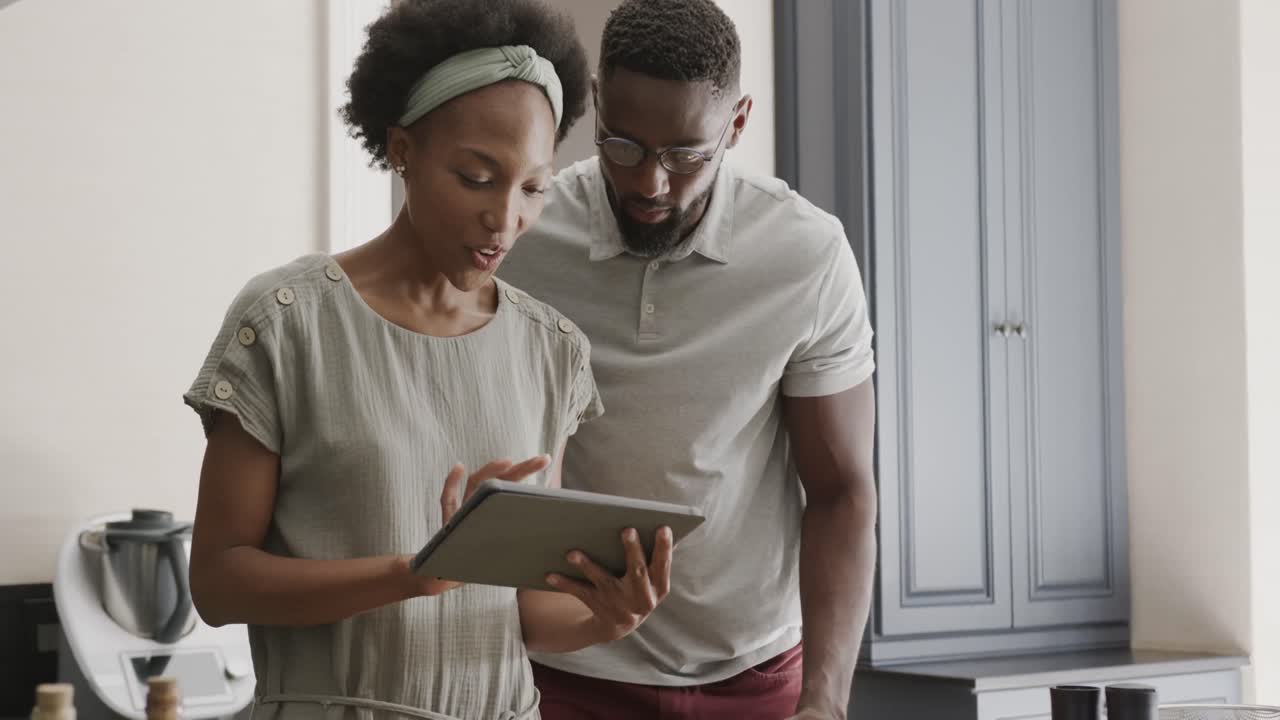 Happy african american couple using tablet in ktichen in slow motion