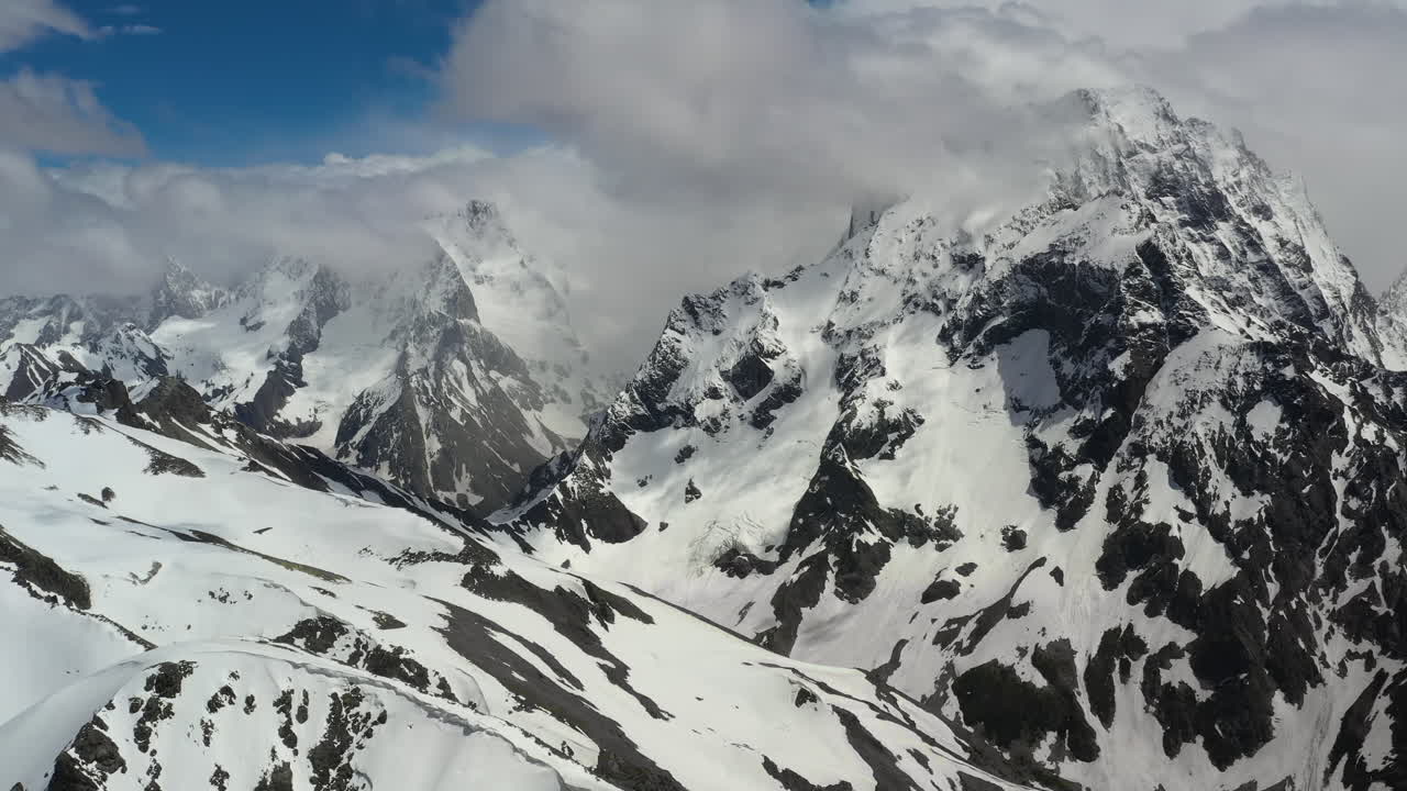 vuelo aéreo a través de nubes montañosas sobre hermosos picos nevados de montañas y glaciares.