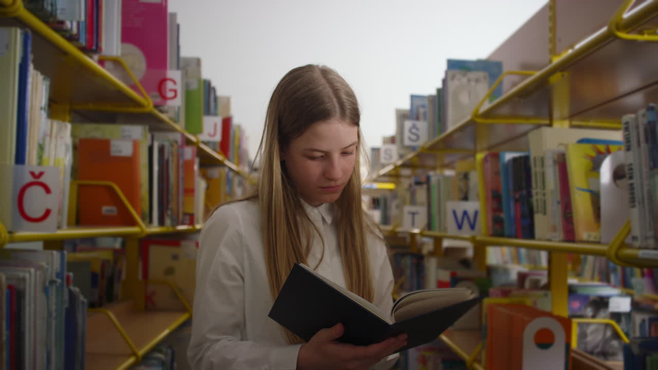 retrato de una adolescente leyendo un libro en la biblioteca de la escuela, disparado a mano
