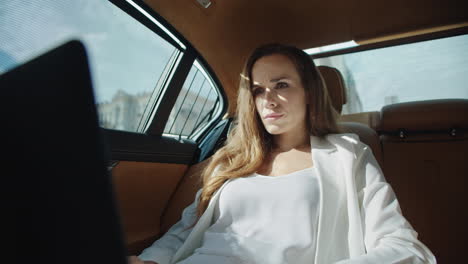 Portrait-of-focused-business-woman-working-on-laptop-in-business-car.