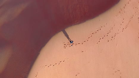 directamente encima de la foto de un hombre parado solo en el desierto con un dron, cerca de omán