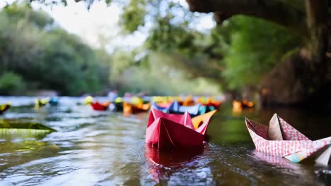 colorful paper boats floating on a river in a forest