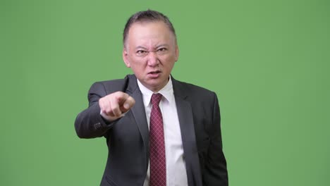 mature angry japanese businessman pointing at camera