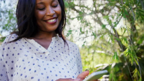 El-Retrato-De-Una-Mujer-Está-Usando-Un-Teléfono-Inteligente-Y-Sonriendo-En-El-Jardín.-