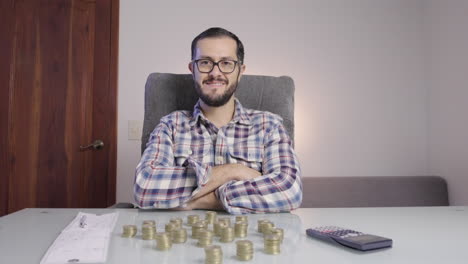 succesful businessman doing accounting and counting coins makes a satisfied face looking to camera