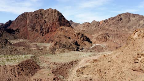 Aerial-drone-view-over-rocky-mountains,-revealing-a-winding-road,-in-Kingman,-USA