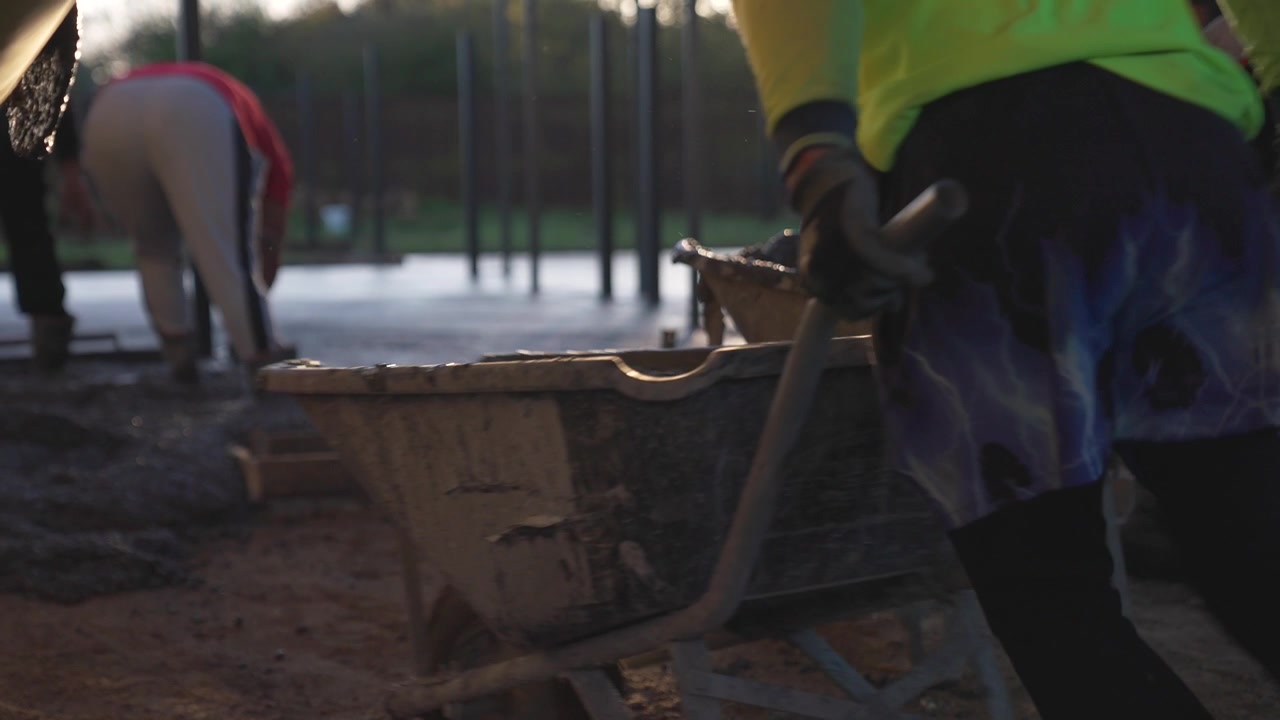 Residential construction site with wheelbarrow filled with concrete at sunrise