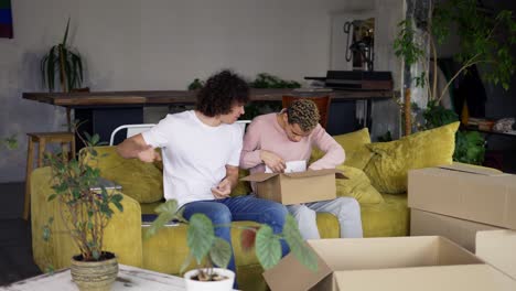 Homosexual-couple-move-to-a-new-apartment,-unpacking-boxes-while-sitting-on-sofa