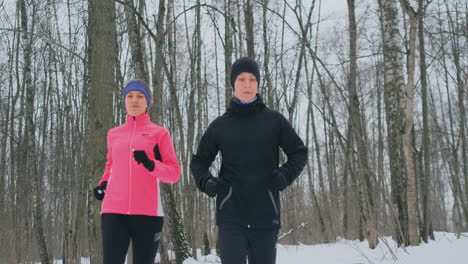 Eine-Schöne-Frau-Und-Ein-Mann-Laufen-Im-Winter-Im-Wald,-Richtige-Ernährung-Und-Ein-Gesunder-Lebensstil.-Zeitlupe.