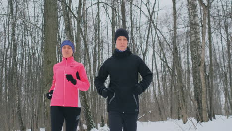 una hermosa mujer y un hombre corren en el bosque en invierno con una nutrición adecuada y un estilo de vida saludable. camara lenta.