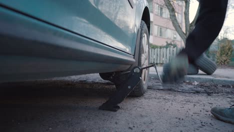 hombre levantando un coche. proceso de cambio de llantas