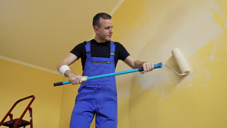 man painting walls in apartment. young man renovating new house and painting interior walls