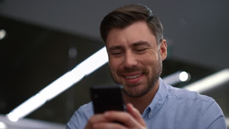 hombre de negocios sonriente enviando mensajes de texto por teléfono hablando en línea en el lugar de trabajo de la compañía corporativa