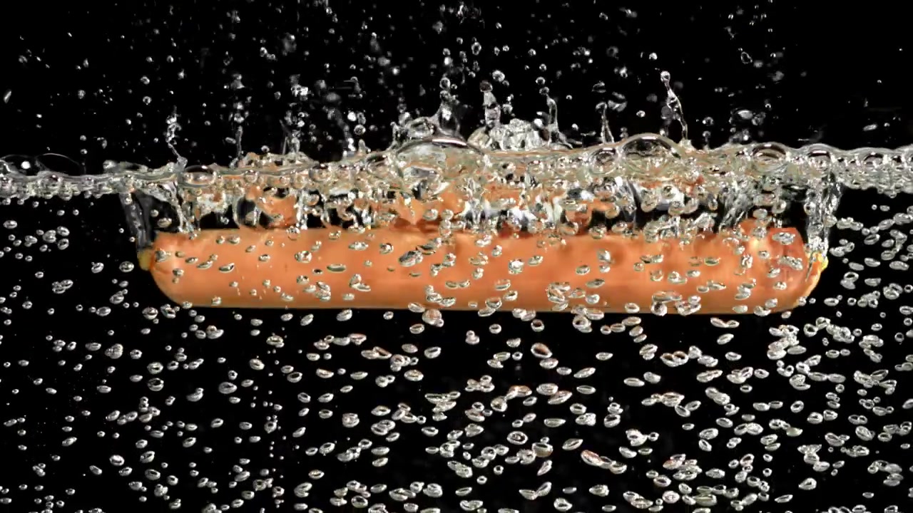 Salsiccia che cade nell'acqua con schizzi e bolle.