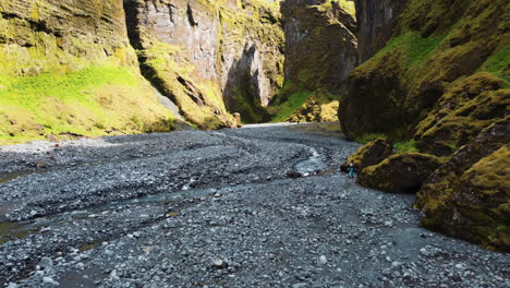 hiker hiding behind a rock near a river on the bottom of a canyon stakkholtsgja in iceland