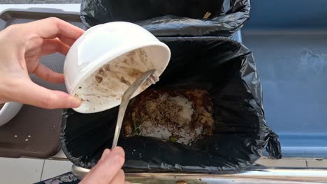 person cleaning bowl by scraping food waste