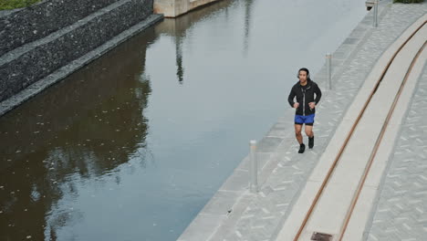 man running on a pathway by a canal