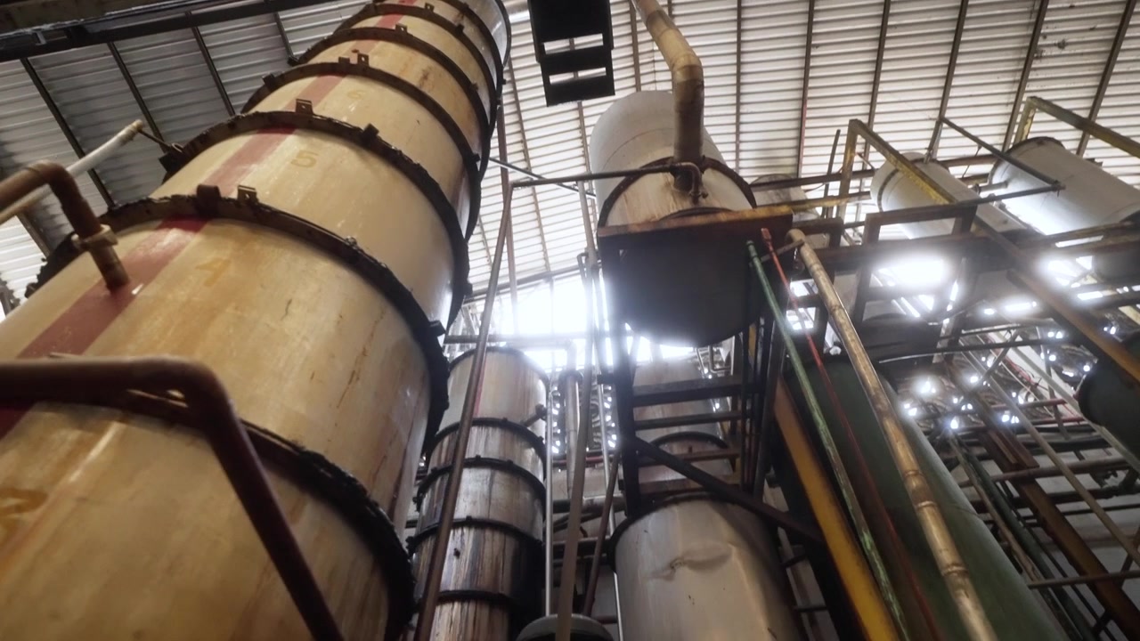 Hautes colonnes de distillation à l'intérieur d'une installation de traitement de distillerie de rhum industrielle, vue en contre-plongée