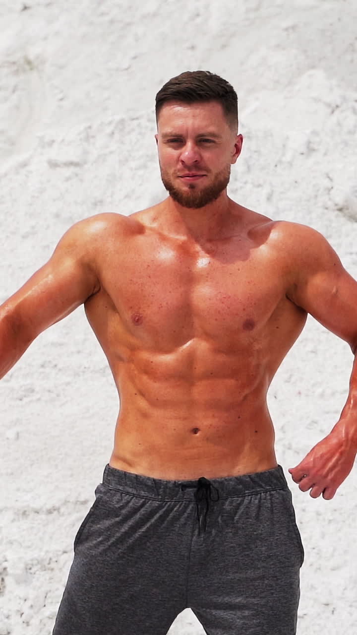 Spots man standing in pose. Well built bodybuilder posing in the mountains Vertical video