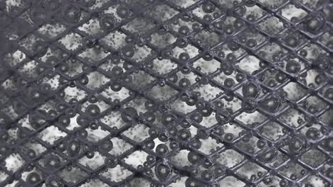 the flow of water directed to the metal mesh causes the bubbling of oxygen bubbles the flow of water directed to the metal mesh causes the bubbling of oxygen bubbles metal mesh in water covered with multicolored iridescent oxygen bubbles due to a blue green blurred background slow motion close up