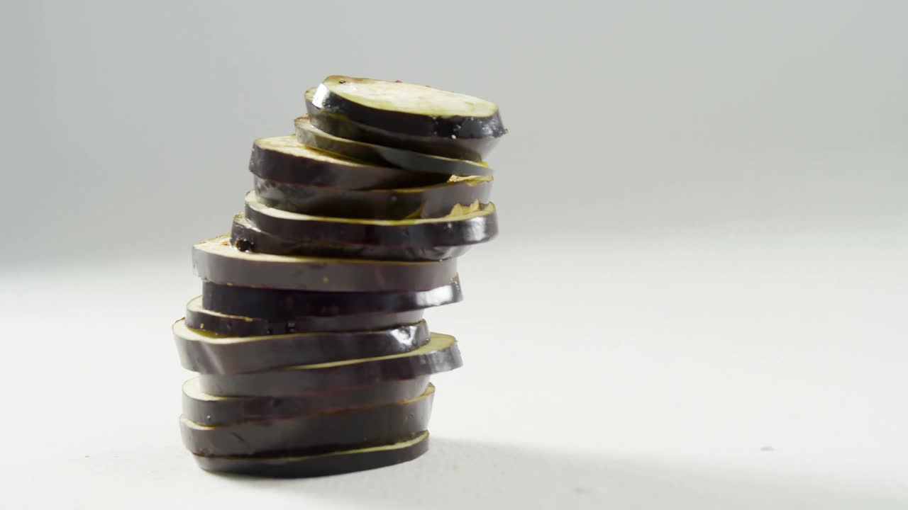 una pila de rodajas de berenjenas dispuestas en una superficie blanca 4k 4k