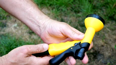 home gardening. human hands insert a yellow garden sprayer.