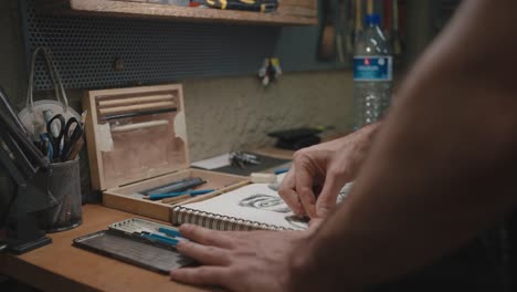 artisan crafting sketches in workshop: low-level shot of hands drawing