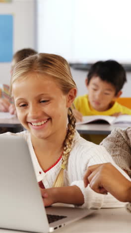 maestro y escolar usando computadora portátil en el aula