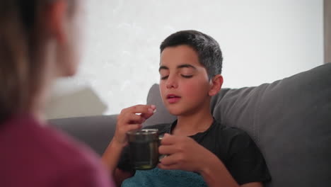 close-up back view of person giving sick boy glass of water while carefully taking his medicine, compassionate care, administering treatment, health recovery