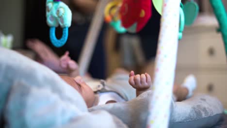 delightful newborn baby girl moving her small legs and hands in cradle looking up at toys