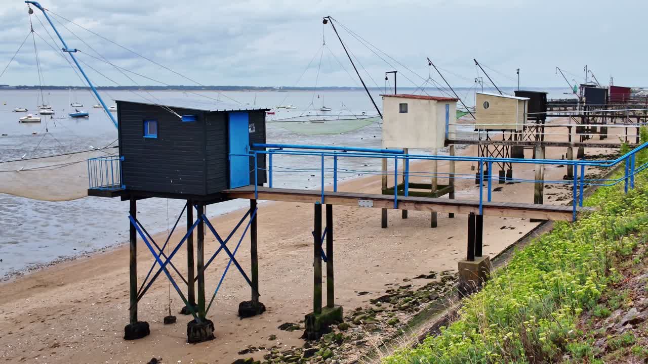 Traditional fishing huts, carrelets on stilts along beach in Saint-Nazaire, France. Panning