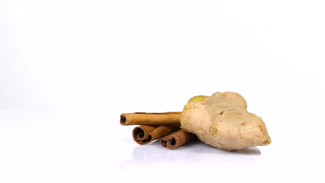 un bucle interminable de palos de canela frescos y jengibre girando sobre un fondo blanco. vista lateral.