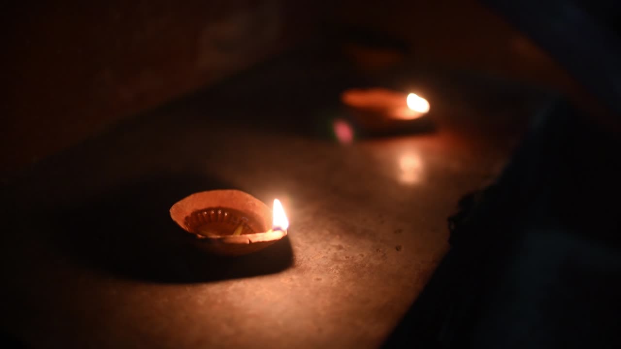 Due Diyas accese sulle scale per la celebrazione del Diwali o del Natale di notte, con le fiamme che si riflettono sul pavimento.